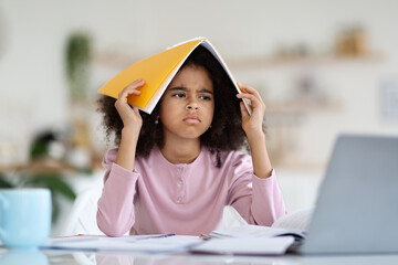 Angry black girl schooler doing homework at home
