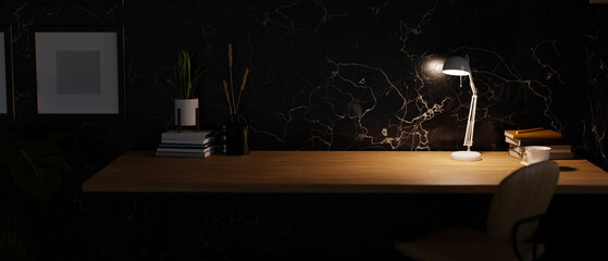 Modern dark home workspace with copy space on wooden tabletop under warm light from table lamp