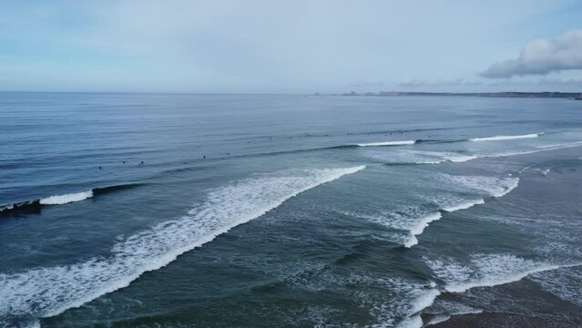Drone circles above the line up in La Palue bay in Brittany in France, many surfers in the waves