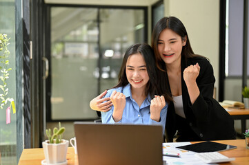 Obraz premium Cheerful young Asian businesswomen making cheer up hands or triumphs gesture
