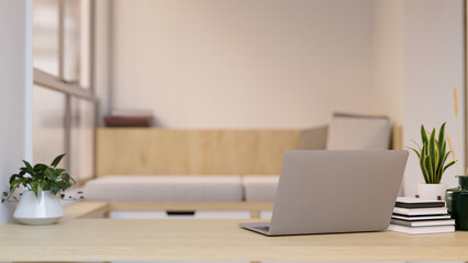 Workspace with laptop and copy space on wood tabletop over blurred minimal living room