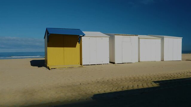 Desolate beach cabins standing next to each other on beach with ocean in the background