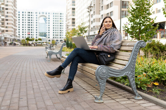 young woman working on a laptop online in the park on a bench, freelance work concept