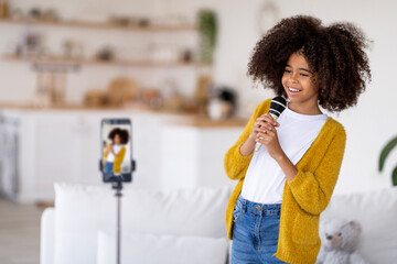 Talented preteen black girl singing karaoke at home