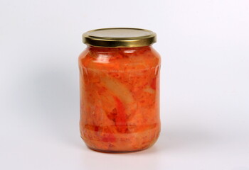 Preparation of canned lecho, canned sweet bell peppers in a glass jar on a white background. Homemade letcho with paprika, tomatoes and carrots