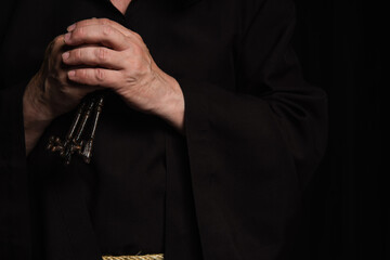 cropped view of senior priest with keys isolated on black.