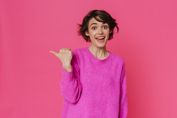 Young excited woman wearing sweater smiling and pointing finger aside