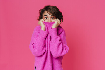 White young woman looking at camera while hiding in her sweater