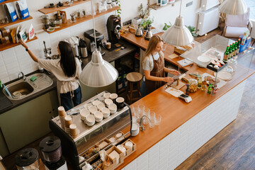 White two barista women smiling while working together in cafe