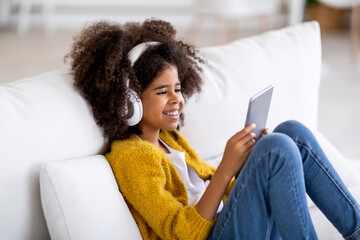 Smiling black child watching cartoons on Internet, home interior