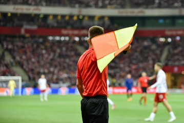 Soccer touchline referee with the flag during match at the football stadium.