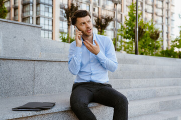 Bristle man talking on cellphone while sitting on stone bench