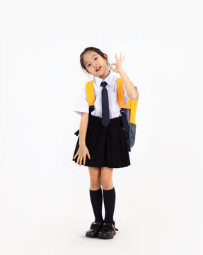 Asian primary school student kid in uniform with yellow backpack posing on white background. Back to school concept.