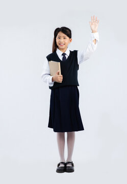 Back to school. Asian junior school student in british uniform holding a book white background.