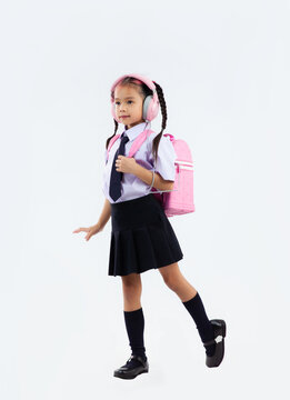 Back to school, junior school student in uniform with pink school bag posing on white background.