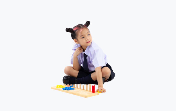 Back to school. Asian kindergarten school student in british uniform sitting and playing toys on white background.