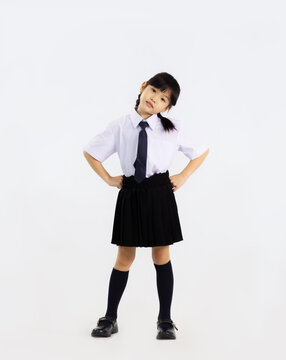 Back to school. Asian girl junior school student in british international uniform posing full length on white background.