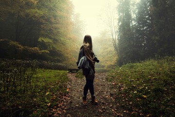Kobieta fotograf w mrocznym, mglistym lesie jesienią.