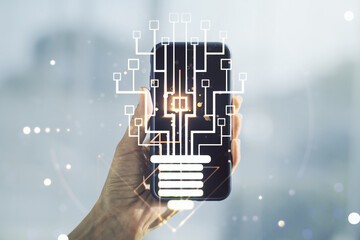 Creative light bulb with chip hologram and hand with cellphone on background, artificial...