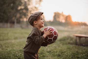 Active leisure. A boy child is playing football outdoors in the countryside.