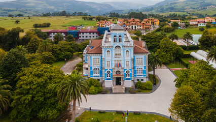 Aerial drone shot flying over the blue Museum of Emigration in the city of Colombres.