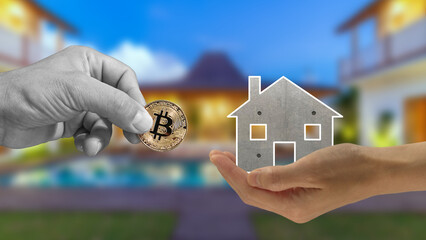 Buying a house with Bitcoin. A hand holds out the house in exchange for Bitcoin, the famous...