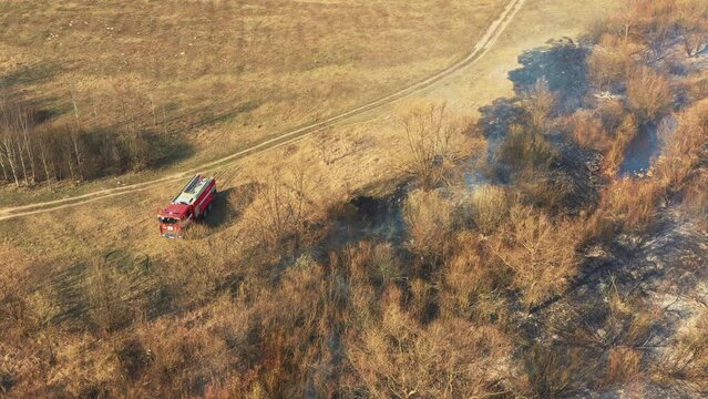 Aerial View. Spring Dry Grass Burns During Drought Hot Weather. Bush Fire And Smoke. Fire Engine, Fire Truck On Firefighting Operation. Wild Open Fire Destroys Grass. Ecological Problem Air Pollution.