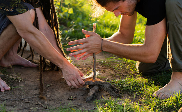 Fire making in the wild (wilderness survival). Two boys trying to make a fire with hand-drill method.