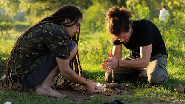 Two young boys trying to make fire with hand-drill method. Survival in the wild concept.