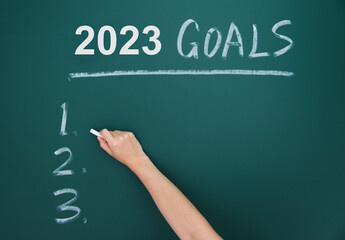 Hand writing 2023 goals on background