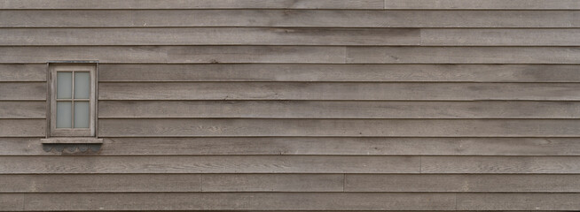 Rustic wood cladding texture with single window, horizontal unpainted old wood planks background,...