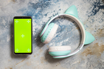 Modern kids headphones and green screen phone on canvas. Horizontal Orientation