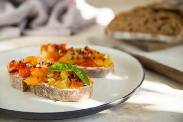 Bruschetta from vegetables on a light plate. Delicious Italian bruschetta antipasti. Beautiful light and shadow pattern.