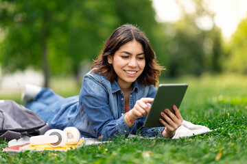 Smiling young arab woman browsing social media on digital tablet outdoors