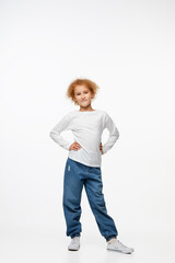 Full-length portrait of little girl, kid in white long sleeve blouse and jeans isolated over white background. Fashion, happy childhood