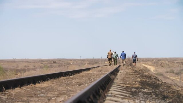 people walk along the railroad tracks on a summer day