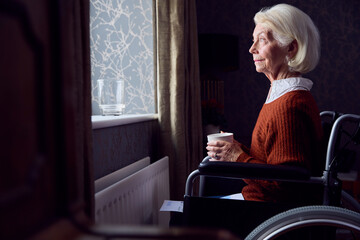 Senior Woman In Wheelchair With Energy Bill By Radiator In Cost Of Living Energy Crisis