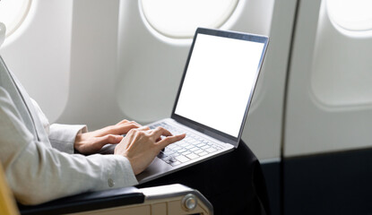 Asian young woman using laptop blank screen sitting near windows at first class on airplane during flight, Traveling and Business concept