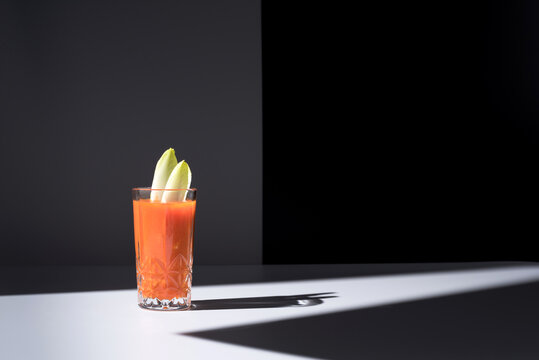 Vaso de jugo de zanahoria con hojas de endibia sobre fondo oscuro