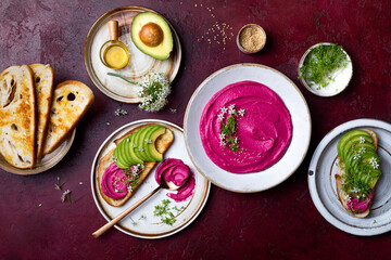 Avocado toast with pink beet hummus spread or dip with edible onion flowers and microgreens. Healthy plant based appetizer, vegan, vegetarian snack