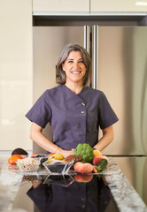 portrait of woman nutritionist in the kitchen with vegetables on the counter top