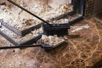 Cleaning the fireplace. Ash and charred piece of wood lying on the blade with a long handle closeup