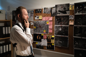 Policeman analyzing information of crime on investigation board, professional working in office at...