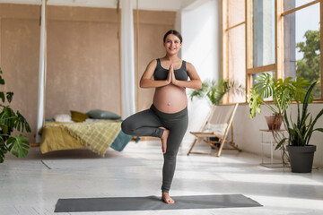 Obraz premium Beautiful Young Expectant Lady Practicing Yoga At Home, Standing In Tree Pose
