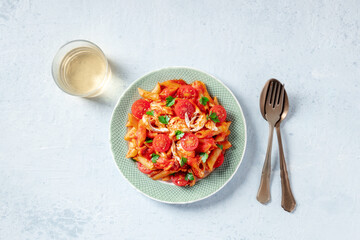 Red pasta with wine. Penne with chicken, tomato sauce, tomatoes, and parsley, overhead flat lay shot with a glass of wine
