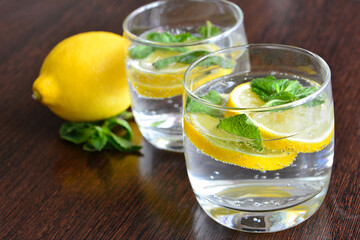 mineral water with slices of lemon and mint leaves in drinking glasses