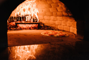 A cooking and baking pizza in a firewood oven. Pizza Margherita, four cheese or meat pizza into the...
