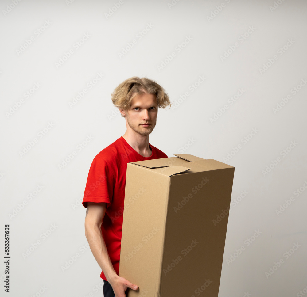 Sticker Portrait of a happy young delivery man in red uniform standing with parcel post box isolated over white background.