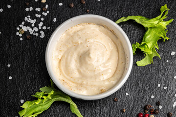 Bowl with tasty white sauce on dark background. Food recipe background. Close up