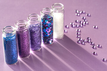 All kinds of glitter products on pink sparkling background. Close-up on vials, bottles with various...
